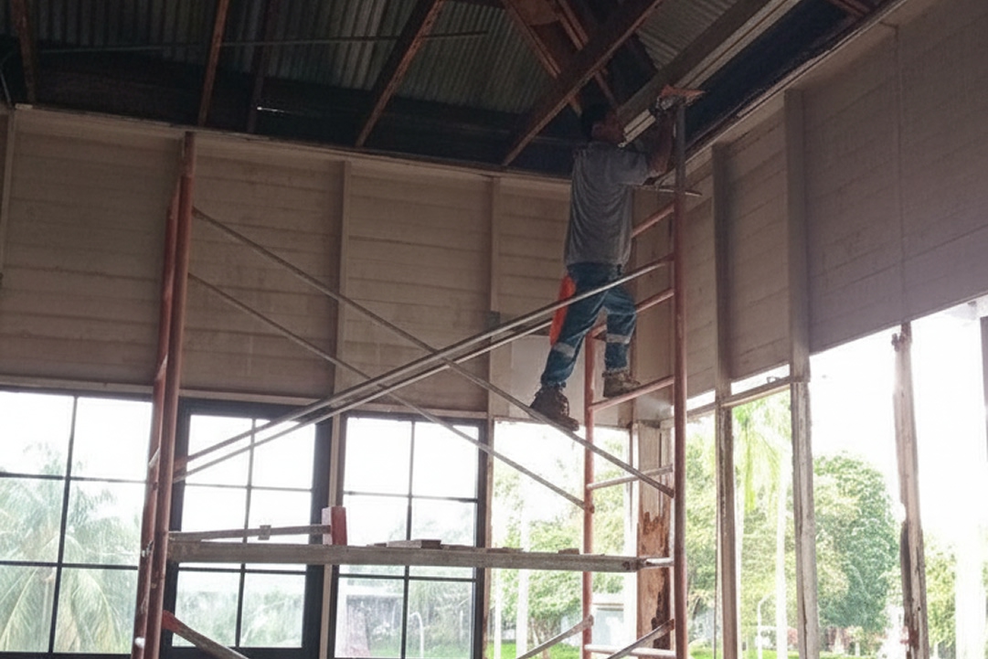 Cuadrilla reparando concreto desprendido y acero expuesto en la fachada de un edificio con andamios