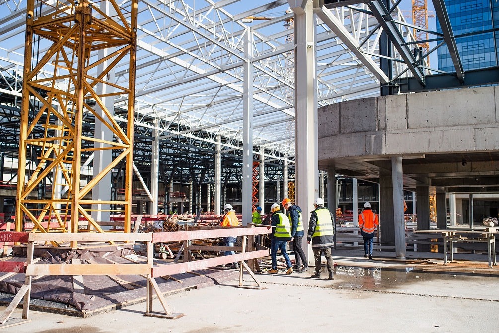 Interior de un local comercial en remodelación con estructura metálica, ductos expuestos y trabajadores instalando paneles